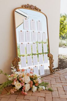 a mirror sitting on top of a brick floor next to a table with flowers and seating