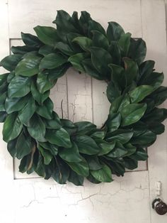 a green wreath hanging on the side of a white door