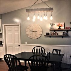 a dining room table with four chairs and a clock on the wall above it,