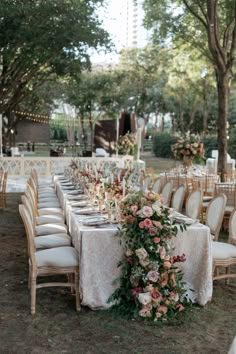 an outdoor table set up with white linens and flowers