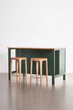 two wooden stools sitting next to a green table