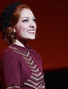 a woman with red hair is smiling at the camera