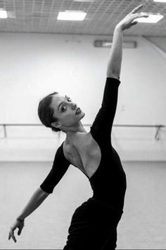 a woman in a black leotard stretching her arms