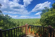 a wooden deck with railings and trees in the background