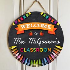 a welcome sign hanging on the front door of a classroom with colorful crayons