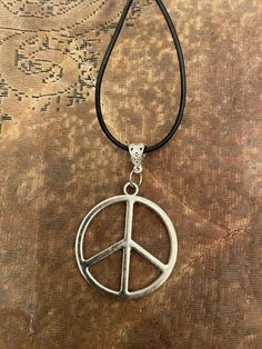 Retro charm. Silver large Round Peace Sign Pendant on a black cord with silver lobster clasp closure. 20" length.  Comes in a velvet pouch and Gift box.  will ship worldwide. Vintage Black Jewelry With Adjustable Cord, Adjustable Peace Sign Necklace, Adjustable Peace Sign Necklace As Gift, Nickel-free Black Round Pendant Charm Necklace, Adjustable Black Charm Necklace, Adjustable Black Necklace With Charms, Black Adjustable Spiritual Charm Necklace, Adjustable Black Spiritual Charm Necklaces, Black Cord Necklace