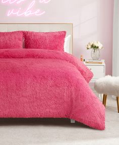 a bright pink bed in a bedroom with a neon sign on the wall behind it