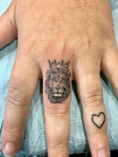 a person's hand with a lion tattoo on it and a heart in the middle