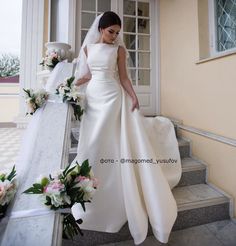 a woman in a wedding dress is standing on some steps