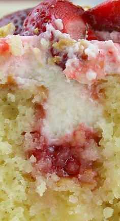 a close up of a piece of cake with strawberries on top and white frosting