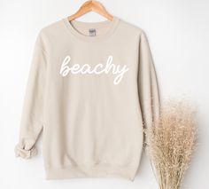 Whether you are taking a sunset stroll on the beach or lounging at home, this beachy sweatshirt will bring you pure comfort.  This unisex heavy blend crewneck is made from polyester and cotton, helping the design come out looking fresh and beautiful. The collar is ribbed knit, so it retains its shape even after washing. There are no itchy side seams on these sweaters. 50% Cotton 50% Polyester Medium-heavy fabric Unisex sizes (See size chart.) Sewn in label Available in 4 colors. Explore all Summ Trendy Summer Beach Sweatshirt, Trendy Beach Sweatshirt For Summer, Letter Print Sweatshirt For Beach Vacation, Spring Beach Cotton Sweatshirt, Casual Summer Beach Sweatshirt, Cotton Sweatshirt With Letter Print, Long Sleeve Sweatshirt For Beach Season, Beach Long Sleeve Sweatshirt, Beach Season Sweatshirt With Letter Print