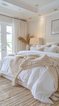 a bed with white linens and pillows in a bedroom next to two doors that lead out to a patio