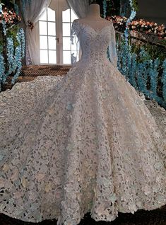 a dress on display in front of a window with flowers and greenery behind it