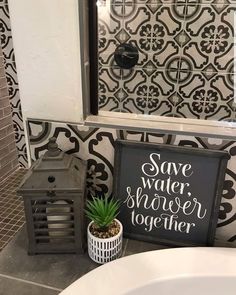 a white sink sitting under a mirror next to a black and white tiled bathroom wall