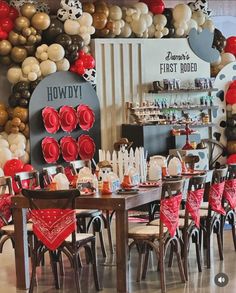 a room filled with lots of tables and chairs covered in red, white and black balloons