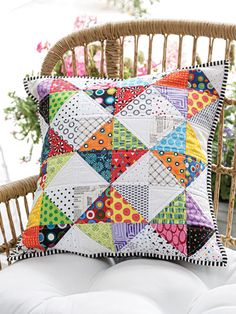 a colorful patchwork pillow on a wicker chair