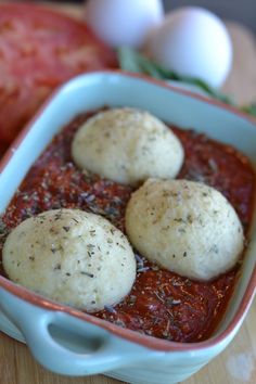 three balls of bread sit in a blue dish next to tomatoes and other food items