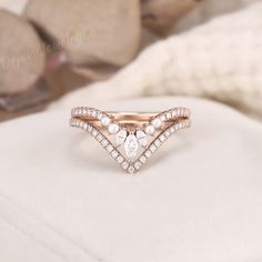 a diamond and pearl ring sitting on top of a white cloth covered cushioned surface