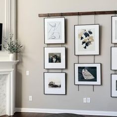 a living room with pictures hanging on the wall and a fire place in front of it