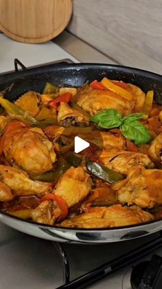 a pan filled with chicken and vegetables on top of a stove