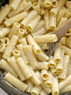 a wooden spoon in a bowl filled with pasta