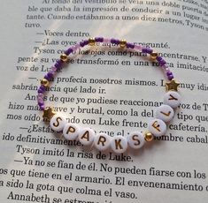 a bracelet with words written in spanish on top of an open book, next to a star