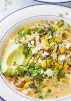 a white bowl filled with soup and topped with avocado