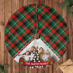 a christmas tree skirt with the family photo on it and presents next to it in front of a wooden background