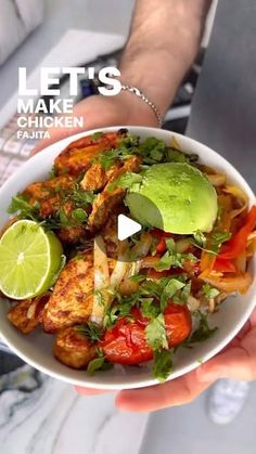 a person holding a white bowl filled with chicken and veggies on top of it