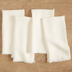 three pieces of white linen on a wooden surface