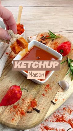 a person dipping ketchup into a bowl on a cutting board with other ingredients