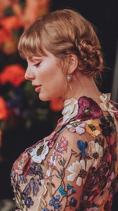 a woman with blonde hair wearing a flowered dress and earrings, looking off to the side