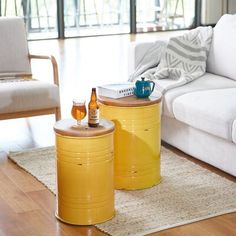 two yellow barrel tables sitting on top of a wooden floor next to a white couch