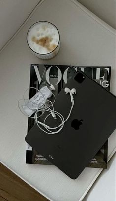 an apple computer sitting on top of a table next to a cup of coffee and headphones