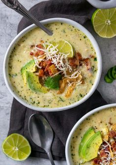 two white bowls filled with soup and topped with bacon, avocado and cheese