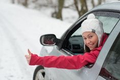 a woman in a car giving the thumbs up while holding her hand out to someone