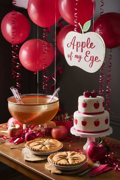 a table topped with pies and cakes next to balloons