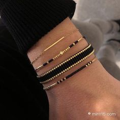 a woman's arm with four different bracelets on her wrist, one is gold and the other is black