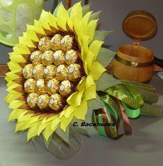 a vase filled with chocolate covered sunflowers on top of a table next to ribbons