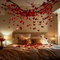 a bed topped with lots of red hearts hanging from the ceiling