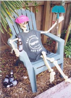 a skeleton sitting on a blue chair with beer in it's mouth and wearing a pink hat