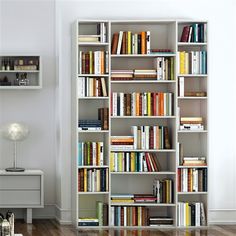 a book shelf filled with lots of books on top of a hard wood floor