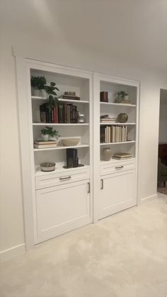 two white bookcases with books on them in a room