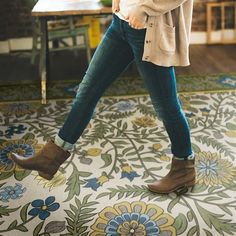 a woman walking across a colorful floor covered in flowers