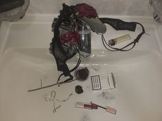 the contents of a woman's purse sitting on top of a bathtub next to other items