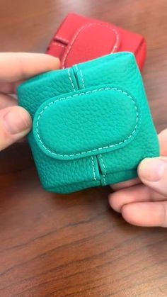 two small wallets being held together on a table