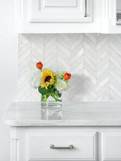 a vase filled with flowers sitting on top of a counter next to a white cabinet