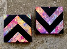 two painted wooden blocks with black and pink designs on them, one has a chevron pattern