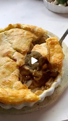 a pie sitting on top of a white plate with a knife in it's mouth