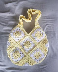 a crocheted yellow and white purse sitting on top of a bed